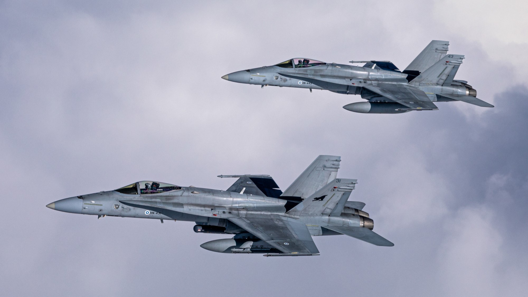 Kaksi F/A-18 Hornet -hävittäjää pilvisellä taivaalla