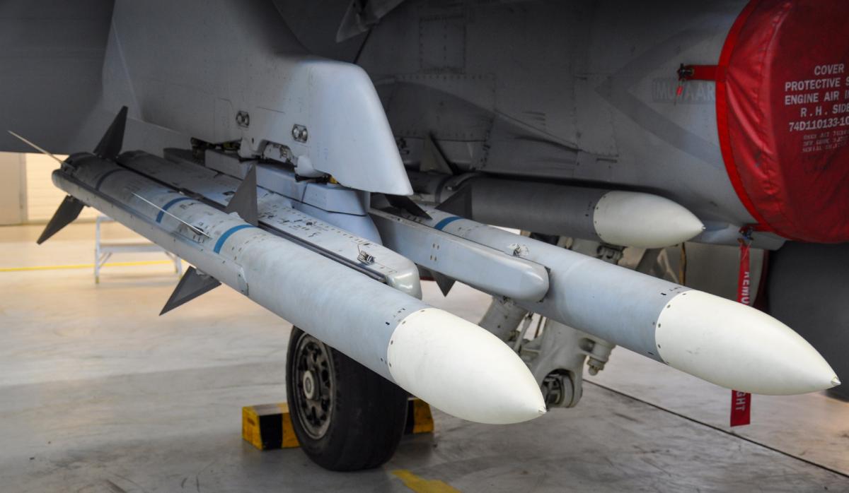 AMRAAM AIM‑120B air‑to‑air missiles mounted under the wing of the F/A‑18 Hornet fighter jet.