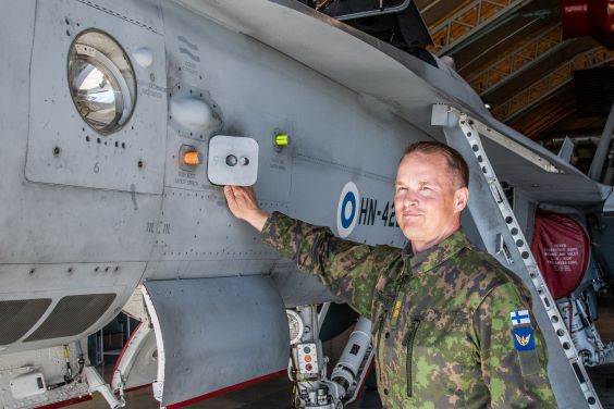 Lähikuva everstiluutnantti Mikko Takalosta nojaamassa toisella kädellään Hornet-hävittäjään.