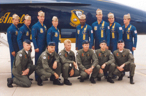 Vanha valokuva, jossa kuusi Suomen ilmavoimien lentäjää poseeraa rivissä takanaan kahdeksan Yhdysvaltalaisen Blue Angels -taitolentoryhmän jäsentä ja yksi heidän hävittäjistään.  