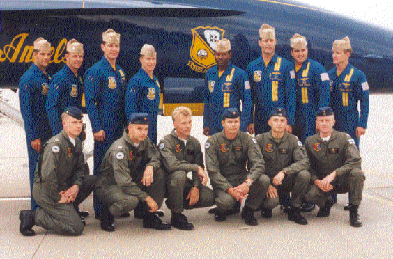 Vanha valokuva, jossa kuusi Suomen ilmavoimien lentäjää poseeraa rivissä takanaan kahdeksan Yhdysvaltalaisen Blue Angels -taitolentoryhmän jäsentä ja yksi heidän hävittäjistään.