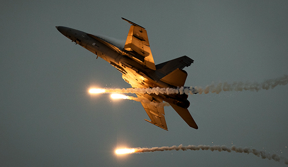 Hornet soihduttaa kirkkaita omasuojaheitteitä esityslennolla Pori Airshow'ssa kesäkuussa 2022. Taustalla harmaa taivas.