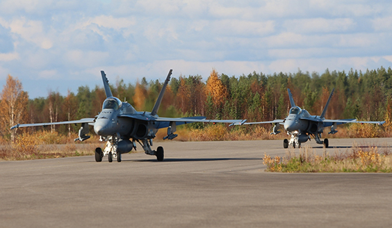 Kaksi F/A-18 Hornet-monitoimihävittäjää kiitoradalla, taustalla syksyistä metsää