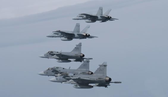 Kaksi suomalaista F/A-18 Hornet- ja kolme ruotsalaista Gripen-hävittäjää lentää muodostelmassa pilvien yläpuolella