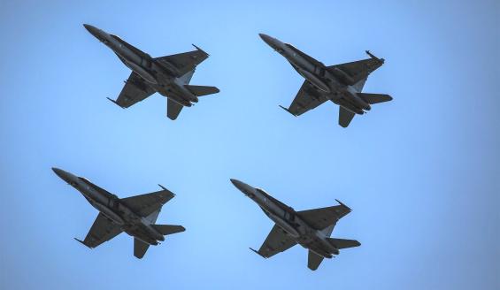 Neljä Ilmavoimien Hornet-hävittäjää lentää ylilentomuodostelmassa pilvettömällä taivaalla