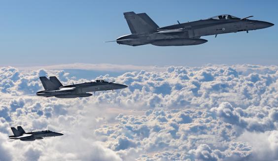 Kolme Suomen Ilmavoimien F/A-18 Hornet -monitoimihävittäjää lentää pilvien yläpuolella
