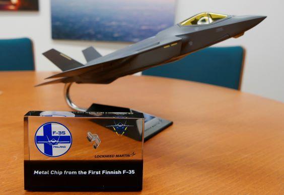 A miniature F-35 and a glass made item with a metal chip from the first Finnish F-35 fighter in it