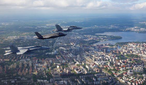 Two Finnish Hornet fighters and one US F-35 fighter flying over a Finnish city in summer 