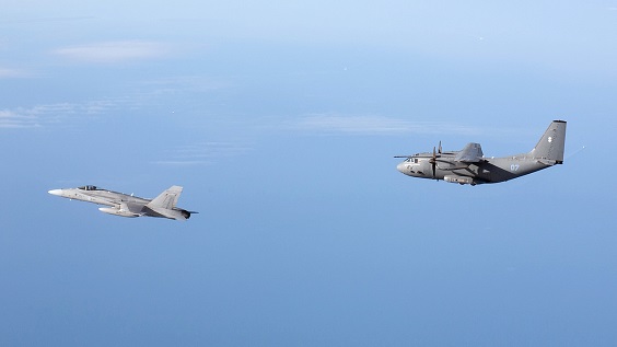 Suomen Ilmavoimien F/A-18 Hornet ja Liettuan ilmavoimien C-27J Spartan lentävät peräkkäin sinisellä taivaalla.