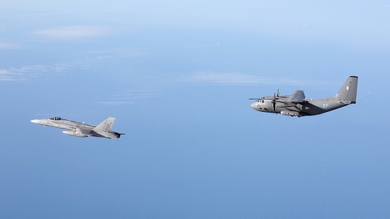 The Finnish Air Force F/A-18 Hornet and a Lithuanian Air Force C-27J Spartan flying together on the blue sky.