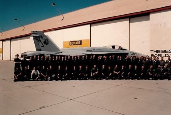 Vanha valokuva Yhdysvalloista. Kuvassa Hornet-hävittäjän edessä poseeraa rivimuodostelmassa useammasta kymmenestä hengestä muodostuva joukko. 