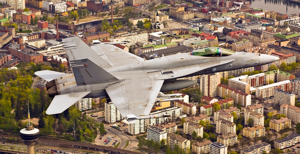 Kuvassa Ilmavoimien Boeing F/A-18 C/D Hornet -monitoimihävittäjä lentää Tampereen kaupungin yllä. Koneen alapuolella näkyy maamerkkinä Särkänniemessä sijaitseva Näsinneula.
