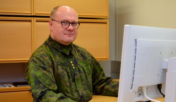 maastopukuinen kapteeni Heikki Paavisto istuu tietokoneen äärellä toimistohuoneessa