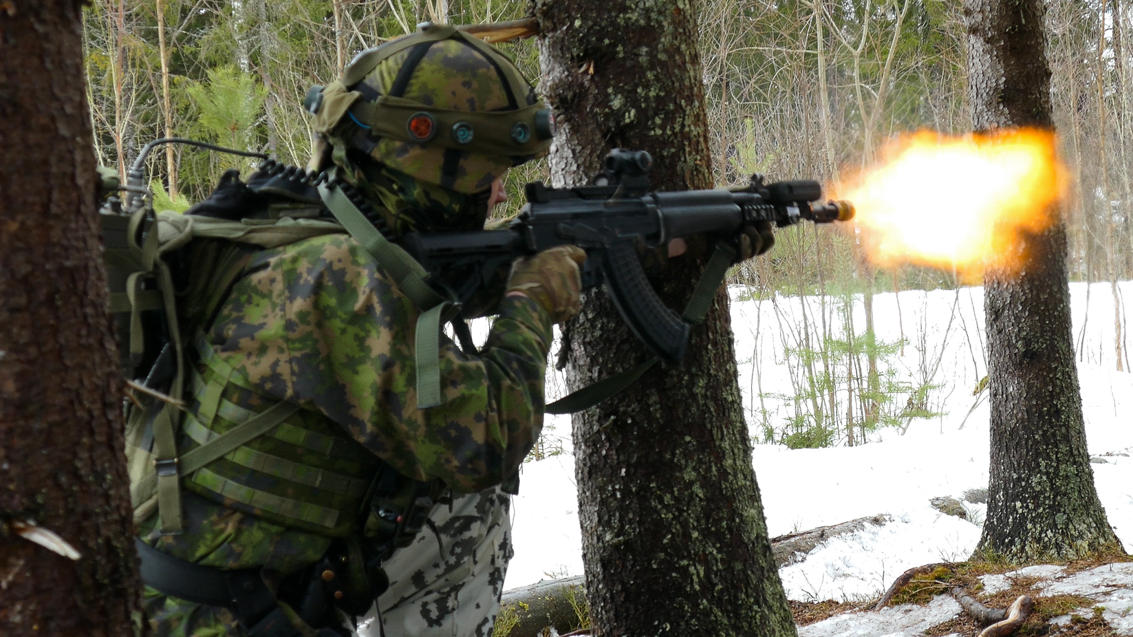 Sotilas tulittaa rynnäkkökiväärillä metsässä. 