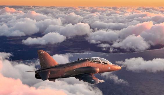 Harmaa Hawk Mk 51 -suihkuharjoituskone lentää ilta-auringon oranssiksi värjäämällä taivaalla pilvien yllä.