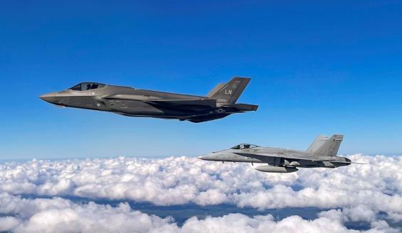 Yhdysvaltalainen F-35-hävittäjä ja suomalainen F/A-18-hävittäjä lentämässä pilvipeitteen yllä.