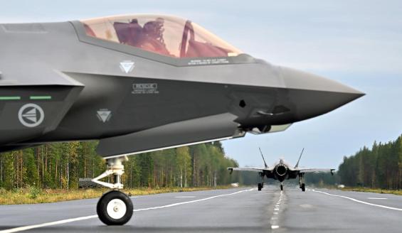 Lähikuva norjalaisen F-35-hävittäjän etuosasta koneen viereltä katsottuna. Taustalla toinen samanlainen hävittäjä rullaa poispäin Tervon maantietukikohdassa. 