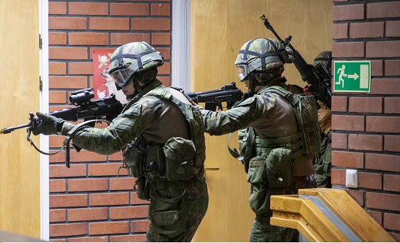 Kolme varusmiestä maastopuvuissa ja rynnäkkökiväärien kanssa harjoittelemassa rakennuksen sisätiloissa. Kuva: Karjalan lennosto