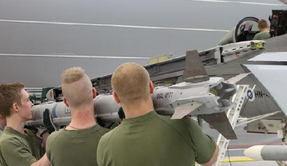 Tre hjälpmekaniker lyfter en värmesökande AIM-9X jaktrobot till avfyringsanordningen vid Hornet-planets vingspets.