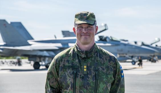 Lähikuva everstiluutnantti Mikko Takalosta takanaan Hornet-hävittäjiä rivissä lentokenttäalueella.. 