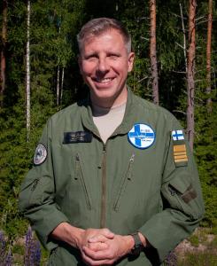 Lähikuvassa eversti Aki Heikkinen taustallaan kesäistä suomalaista sekametsää.