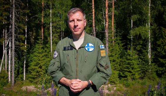 Henkilökuvassa eversti Aki Heikkinen taustallaan kesäistä suomalaista sekametsää.
