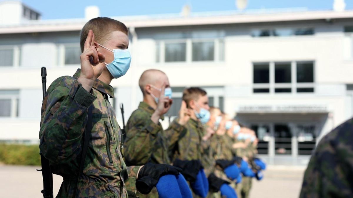 Rivi Ilmasotakoulun alokkaita maastopuku päällä ja maskit kasvoilla. Kaikilla on oikea käsi valanvannomisasennossa.