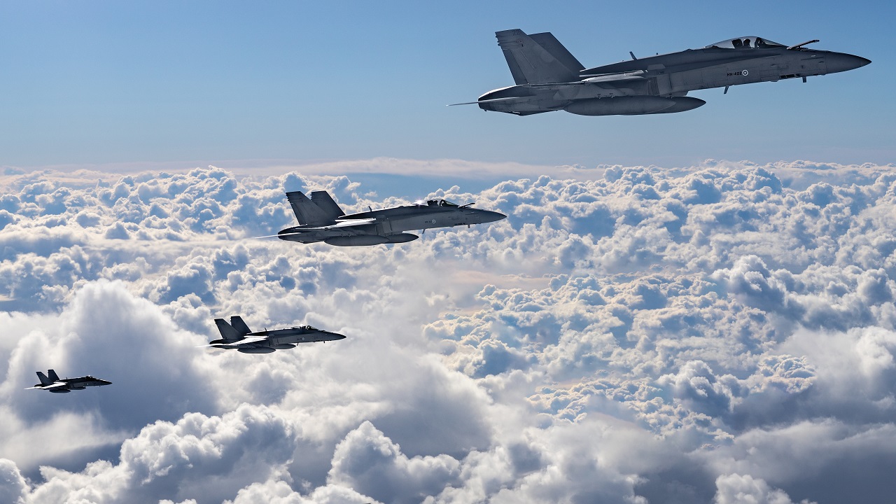 Fyra Flygvapnets F/A-18 Hornet-jaktplaner flyger över molnen.