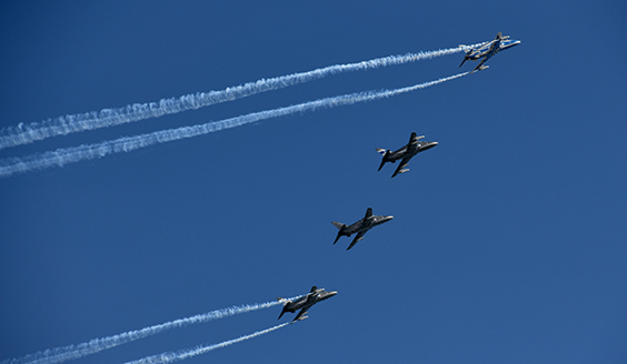 Neljä Hawkia lentää vierekkäin. Reunimmainen kone on juhlamaalattu sinivalkoiseksi, muut ovat harmaita.