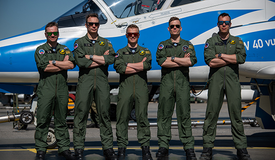 Midniht Hawks -taitolento-osaston lentäjät seisovat Hawk-suihkuharjoituskoneen edessä rivissä ja aurinkolasit päässä.